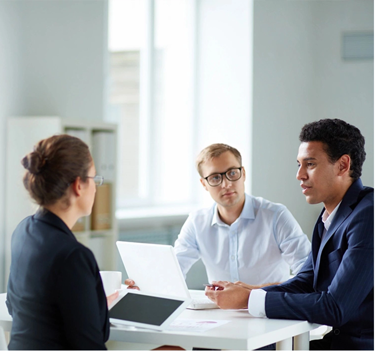 Three people sitting at a table with papers in front of them.