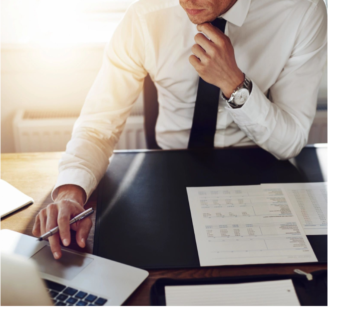 A man sitting at a table with papers and a laptop.