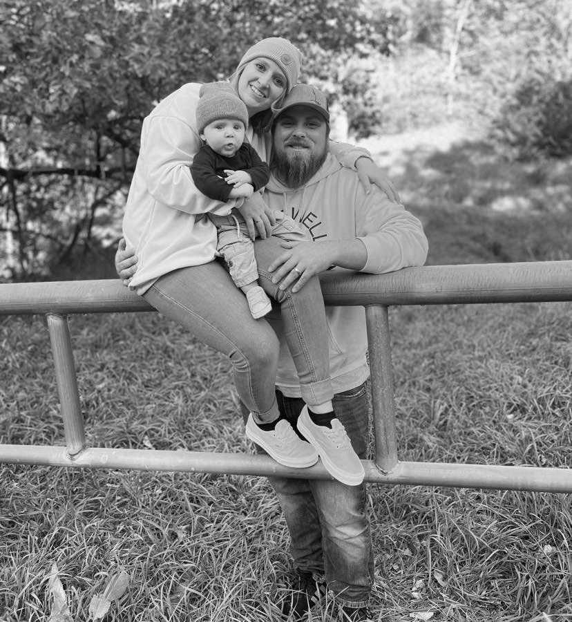 A man and woman holding a child on top of a fence.