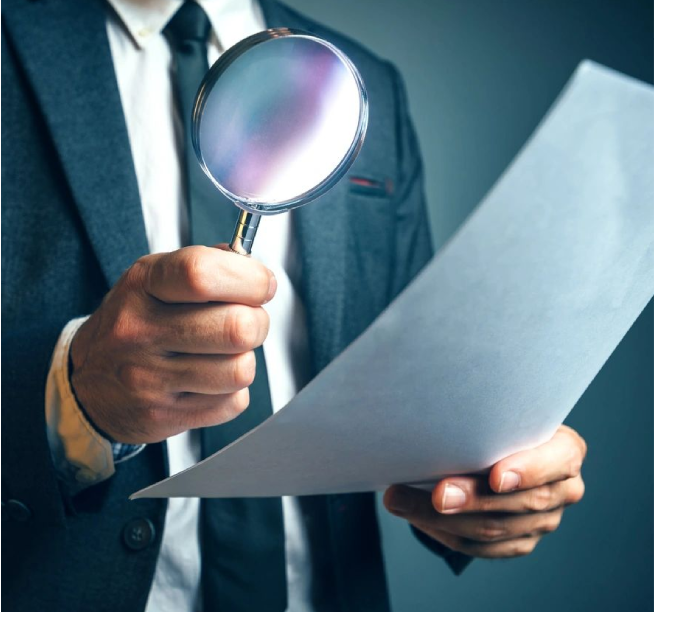 A man holding a magnifying glass and paper.